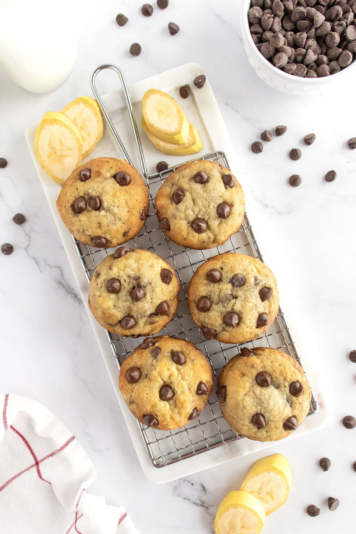 Six banana chocolate chip muffins on a wire rack. 