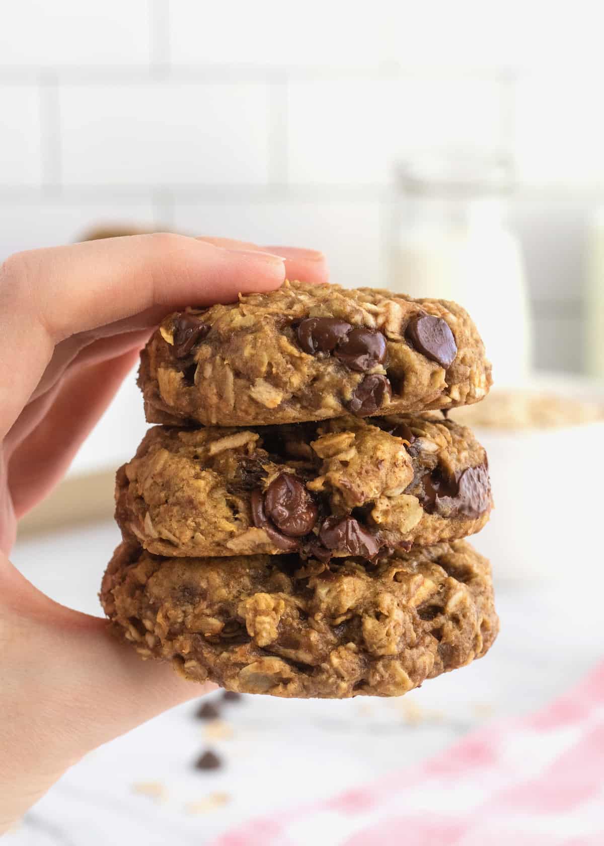 A hand holding three Breakfast Cookies stacked on top of each other.