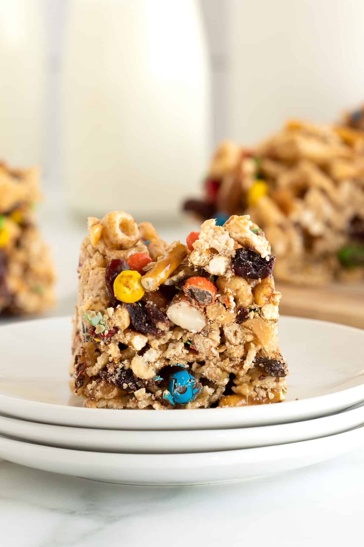 A cereal snack bar with M&Ms and nuts on a plate. 