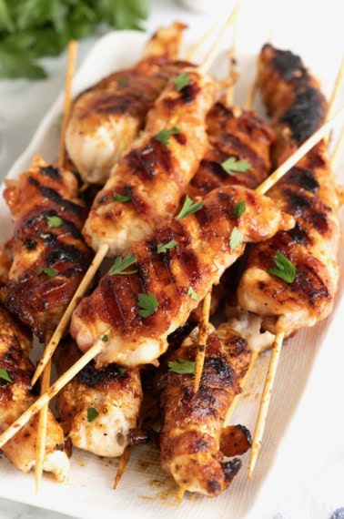 Chicken skewers wrapped in bacon with grill marks on them.