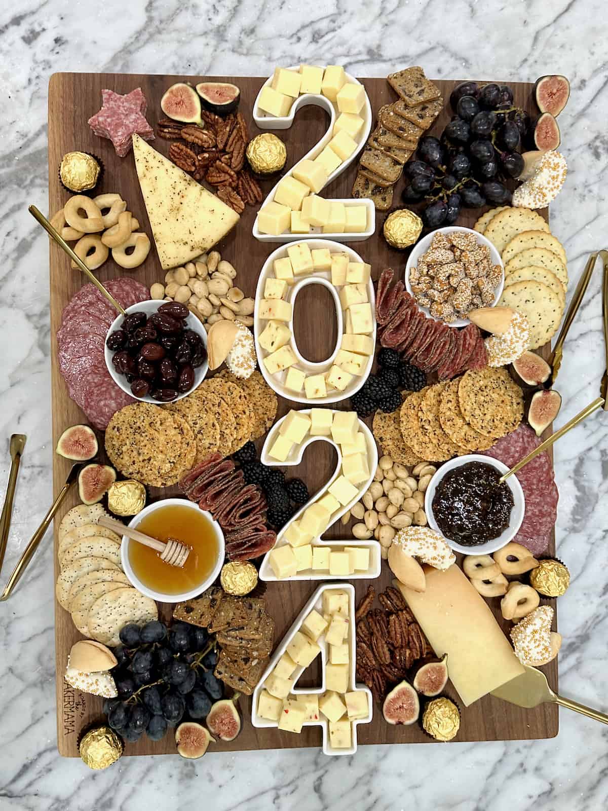 A large wood cheese board with 2024 spelled out in number dishes full of cheese cubes.