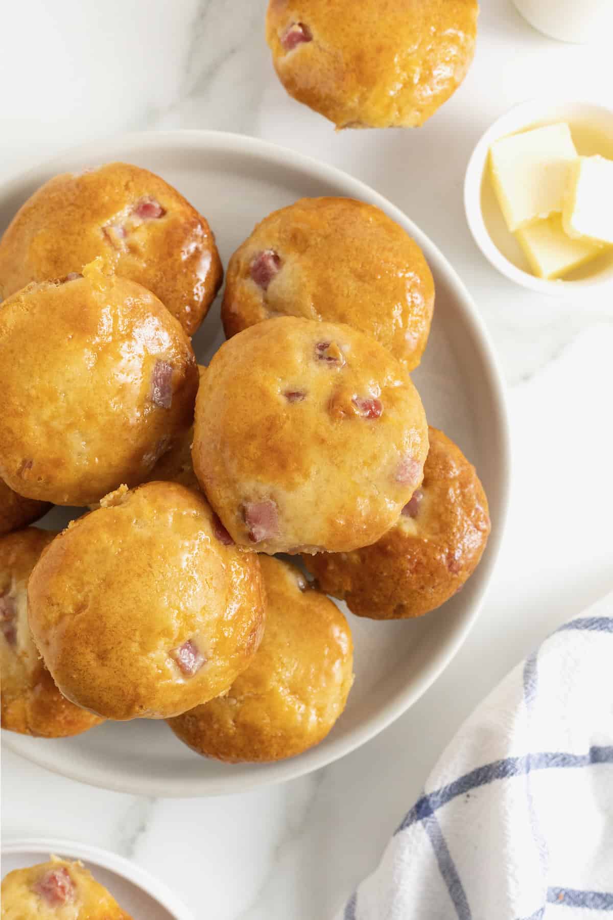 A white platter of honey glazed ham and cheddar muffins.