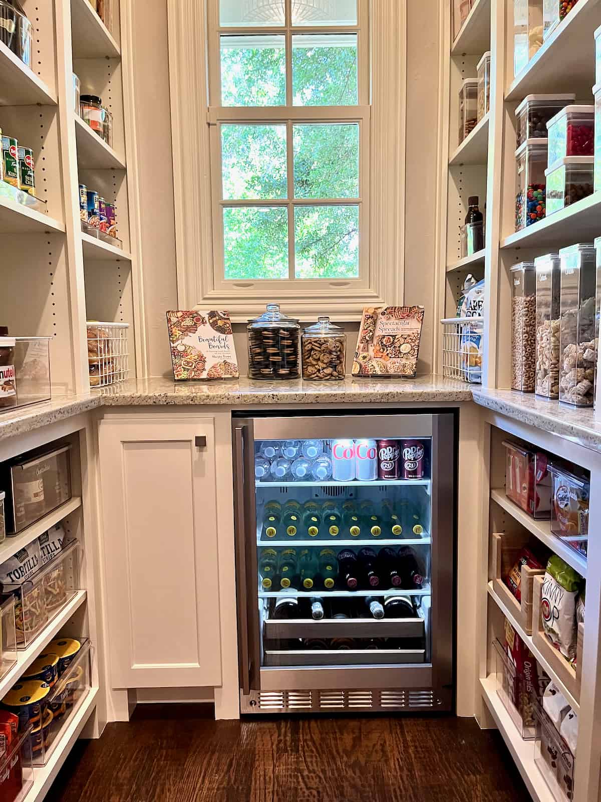 Organized walk-in pantry with clear storage containers and drink refrigerator.