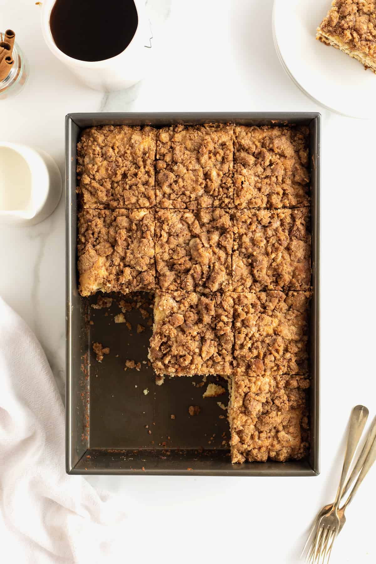 A rectangle metal baking pan of coffee cake with three slices cut out.