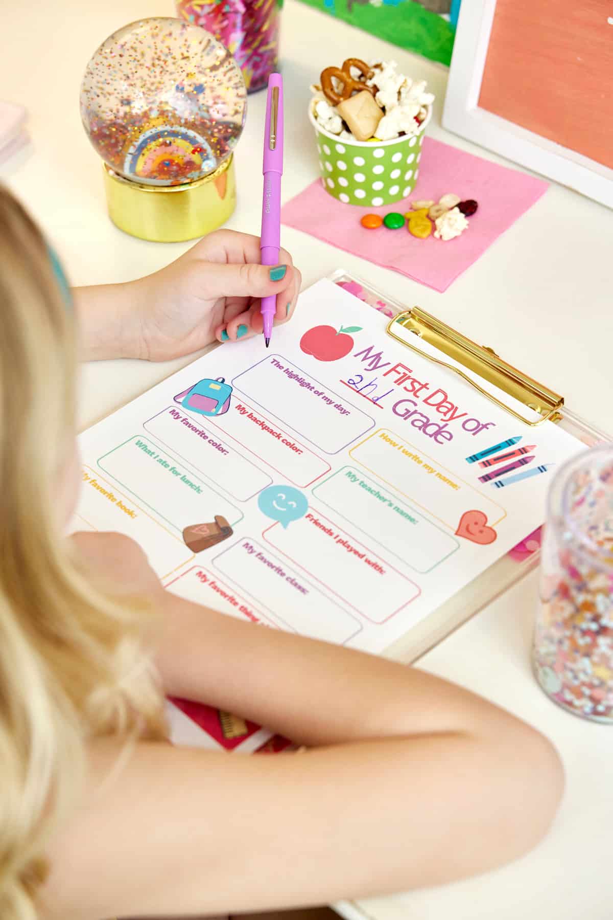 A young girl filling out a My First Day questionnaire and eating a popcorn snack mix.