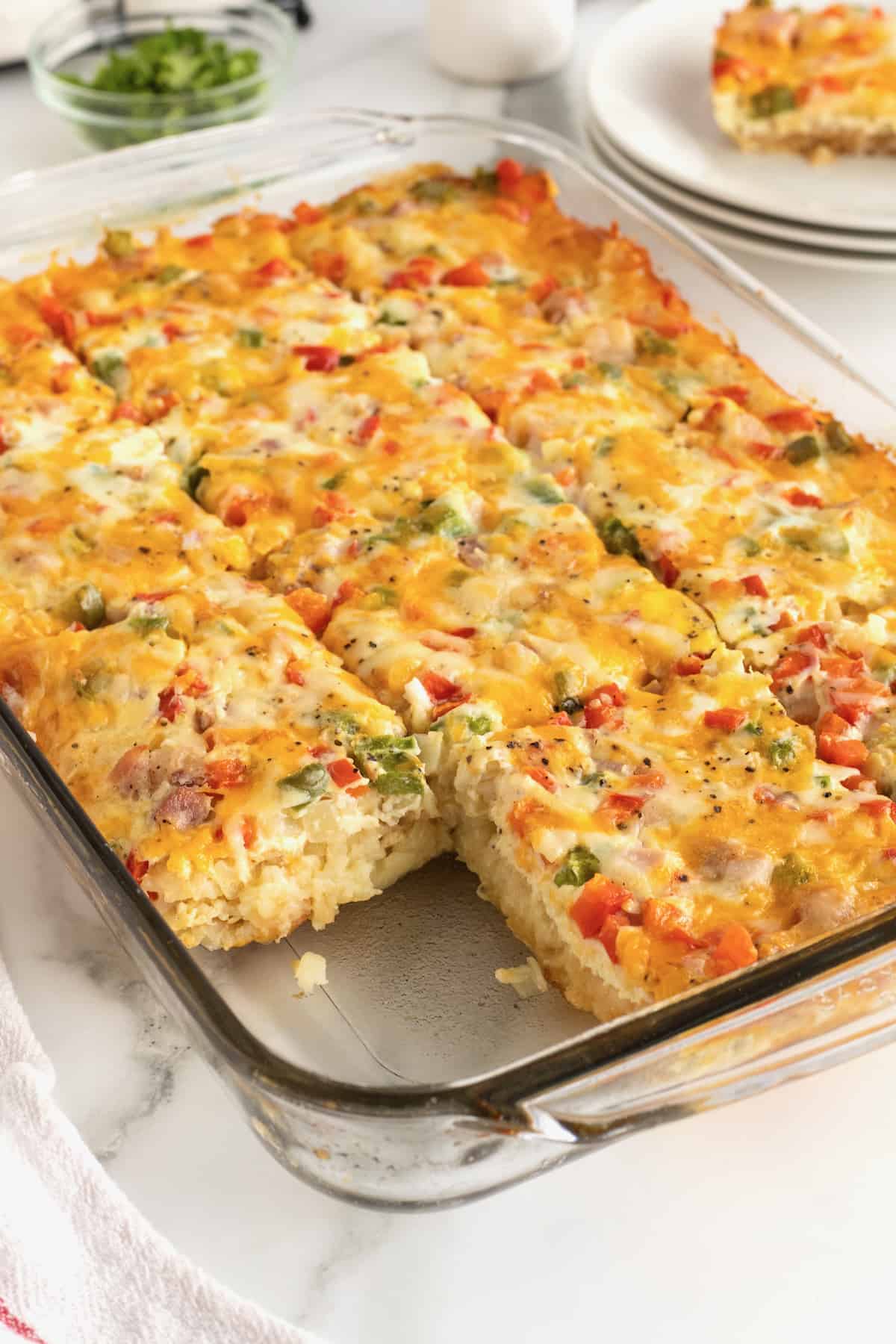 A clear glass baking dish with hash brown breakfast casserole.