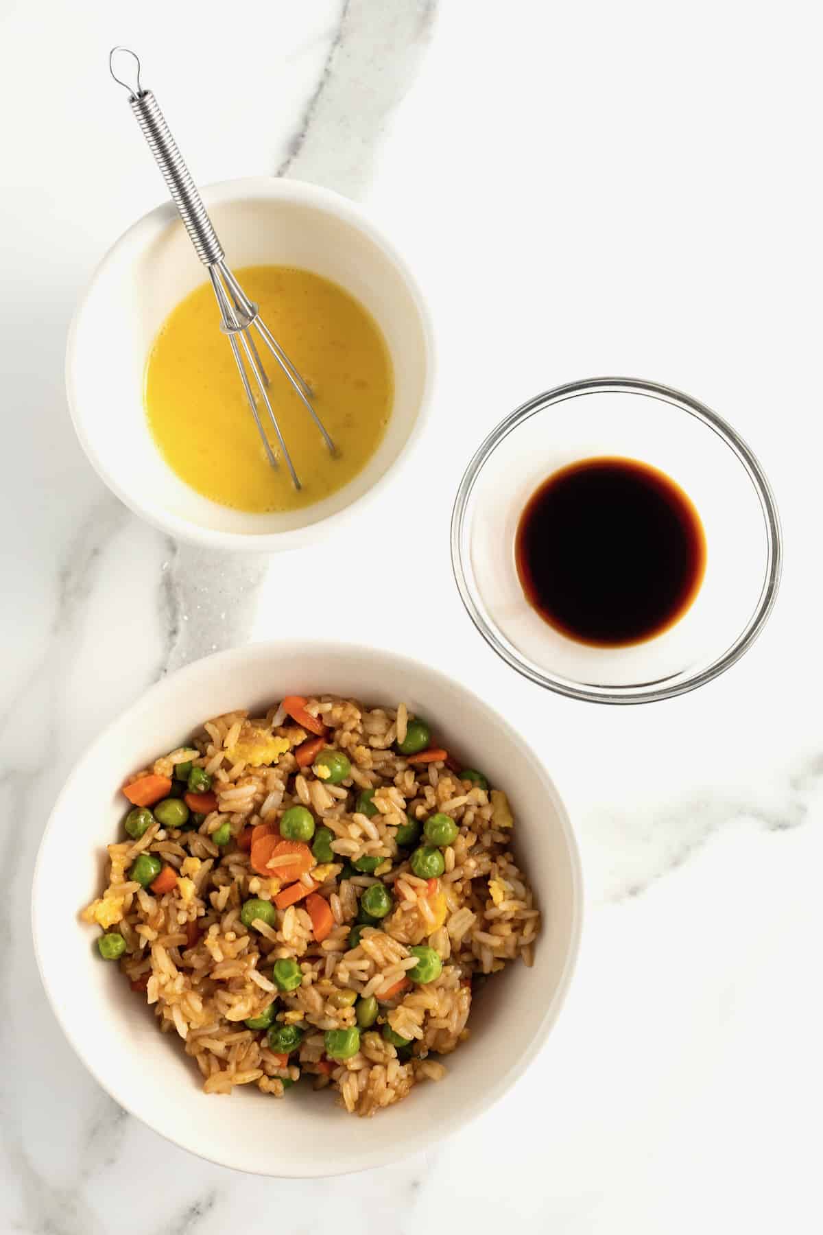 Leftover fried rice, beaten egg, and soy sauce in small glass dishes.