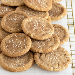 Snickerdoodle cookies sprinkled with sea salt piled on a parchment lined cooling rack.