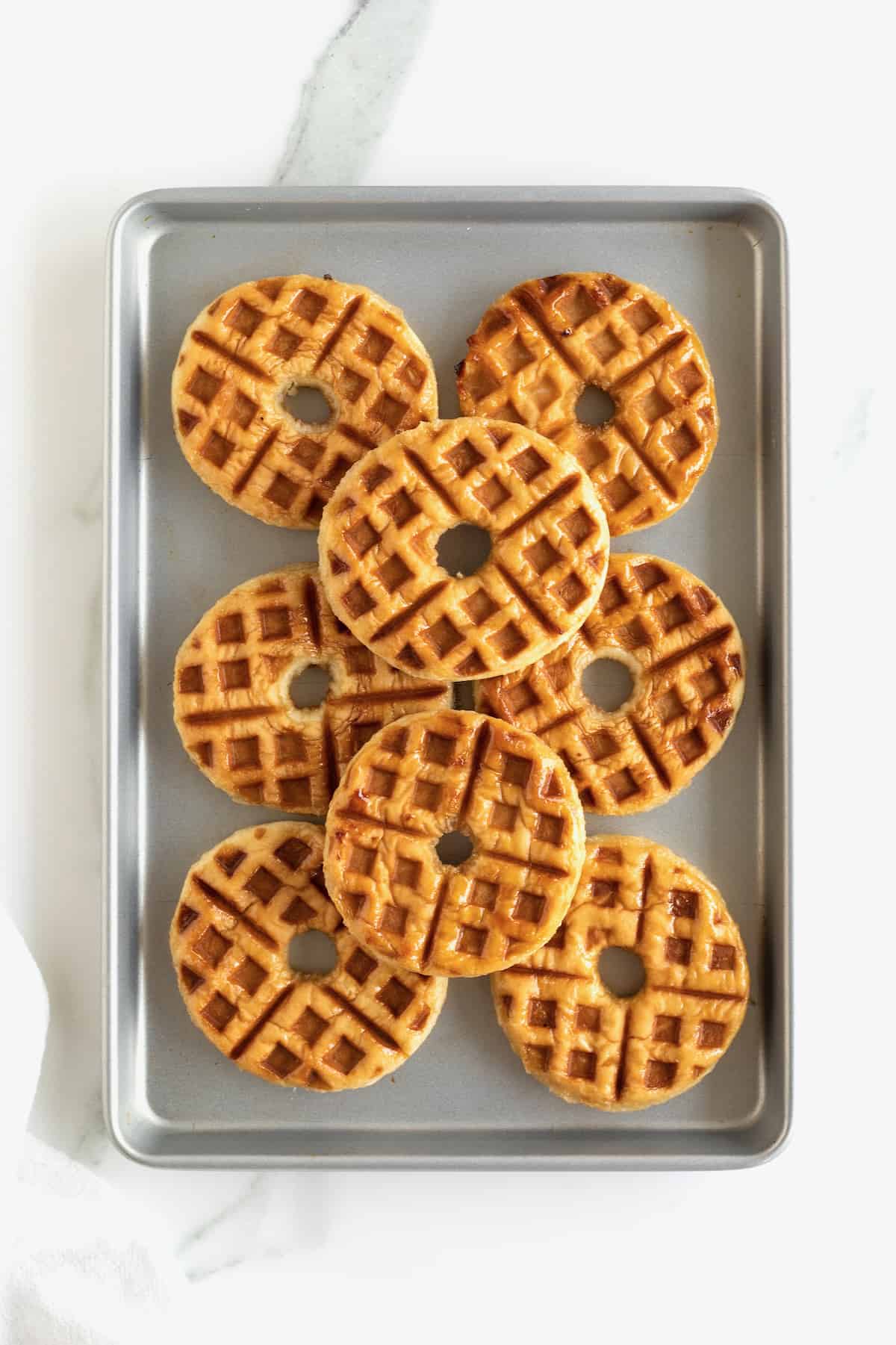 A baking tray filled with 8 hot donut waffles.