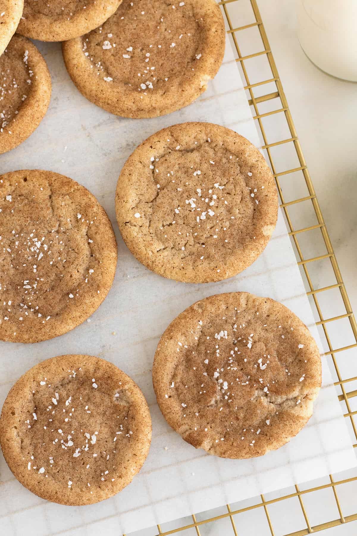 Brown Butter Snickerdoodle cookies sprinkled with sea salt on a parchment lined cooling rack.
