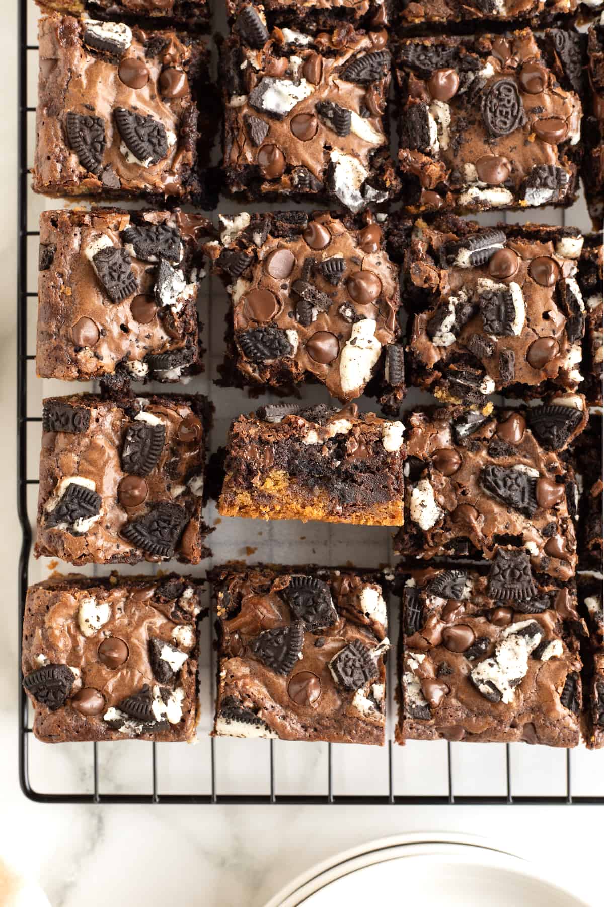 Nine three layer brownies on a parchment lined cooling rack.