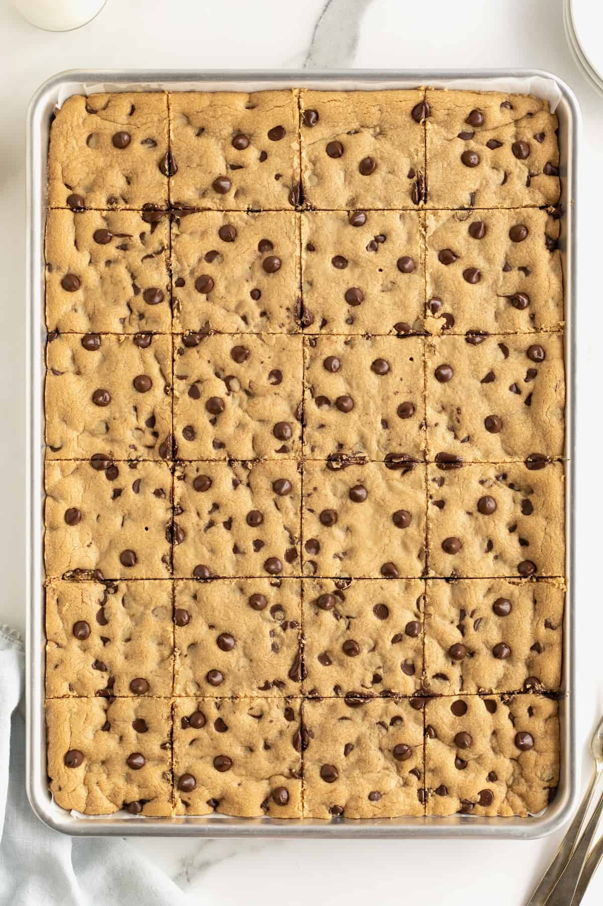 A sheet pan of peanut butter chocolate chip cookies cut into squares.