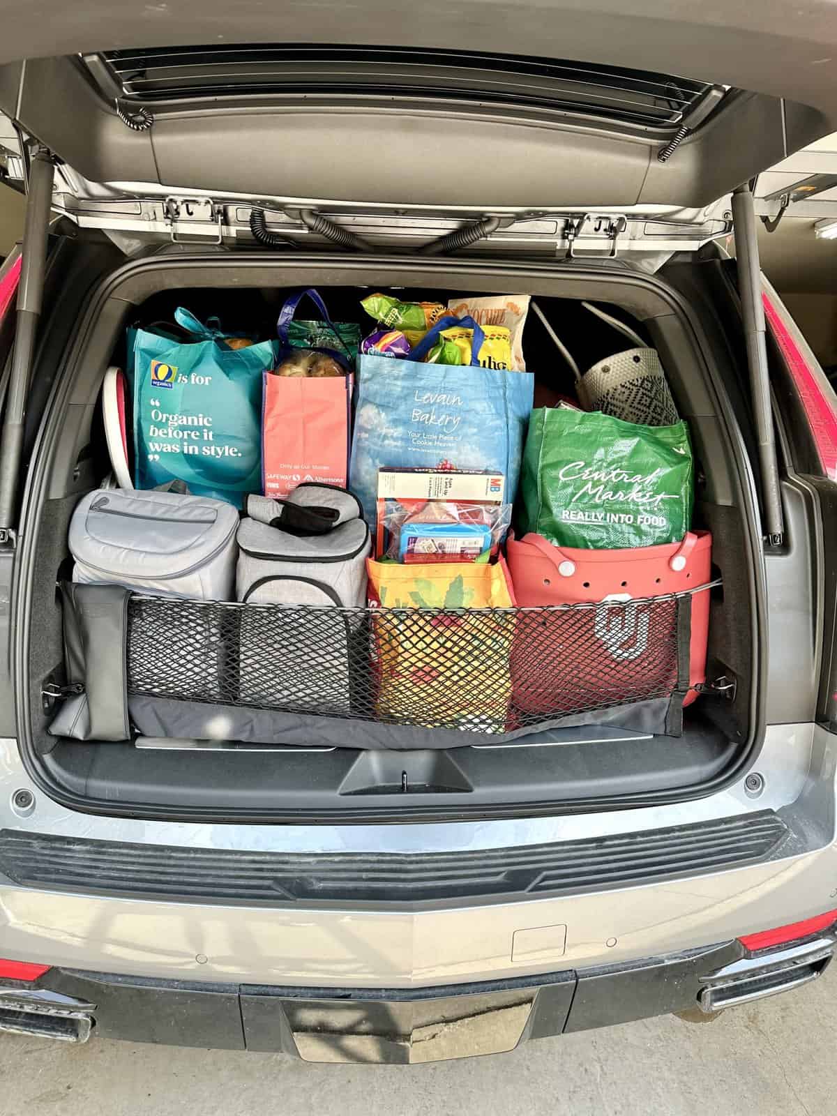 The back of an SUV loaded up with bags of groceries and coolers.
