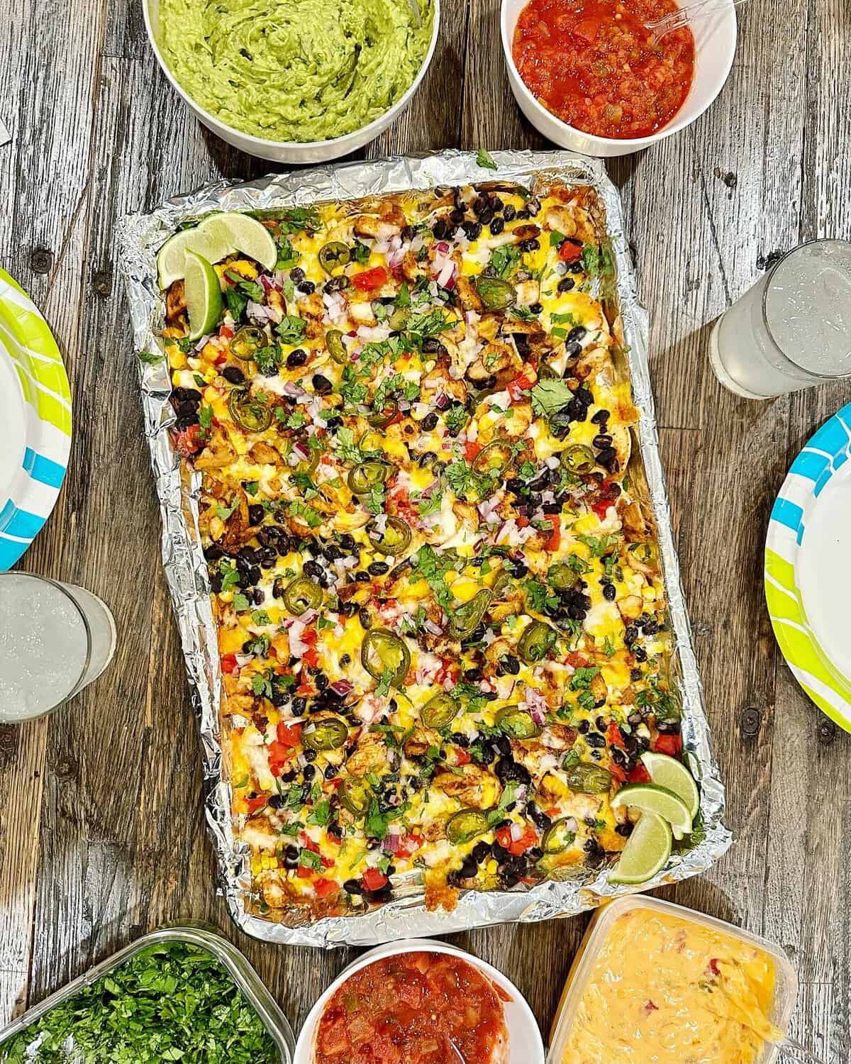 A sheet pan lined with foil  filled with nachos.