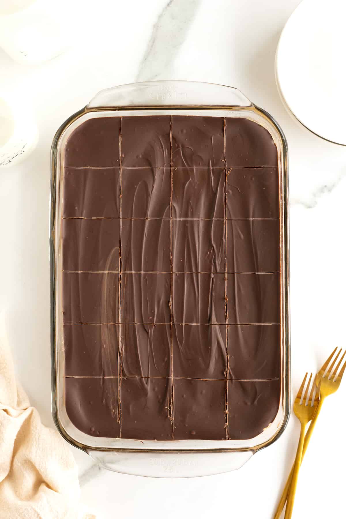 A glass baking dish with chocolate covered peanut butter bars cut into even squares.