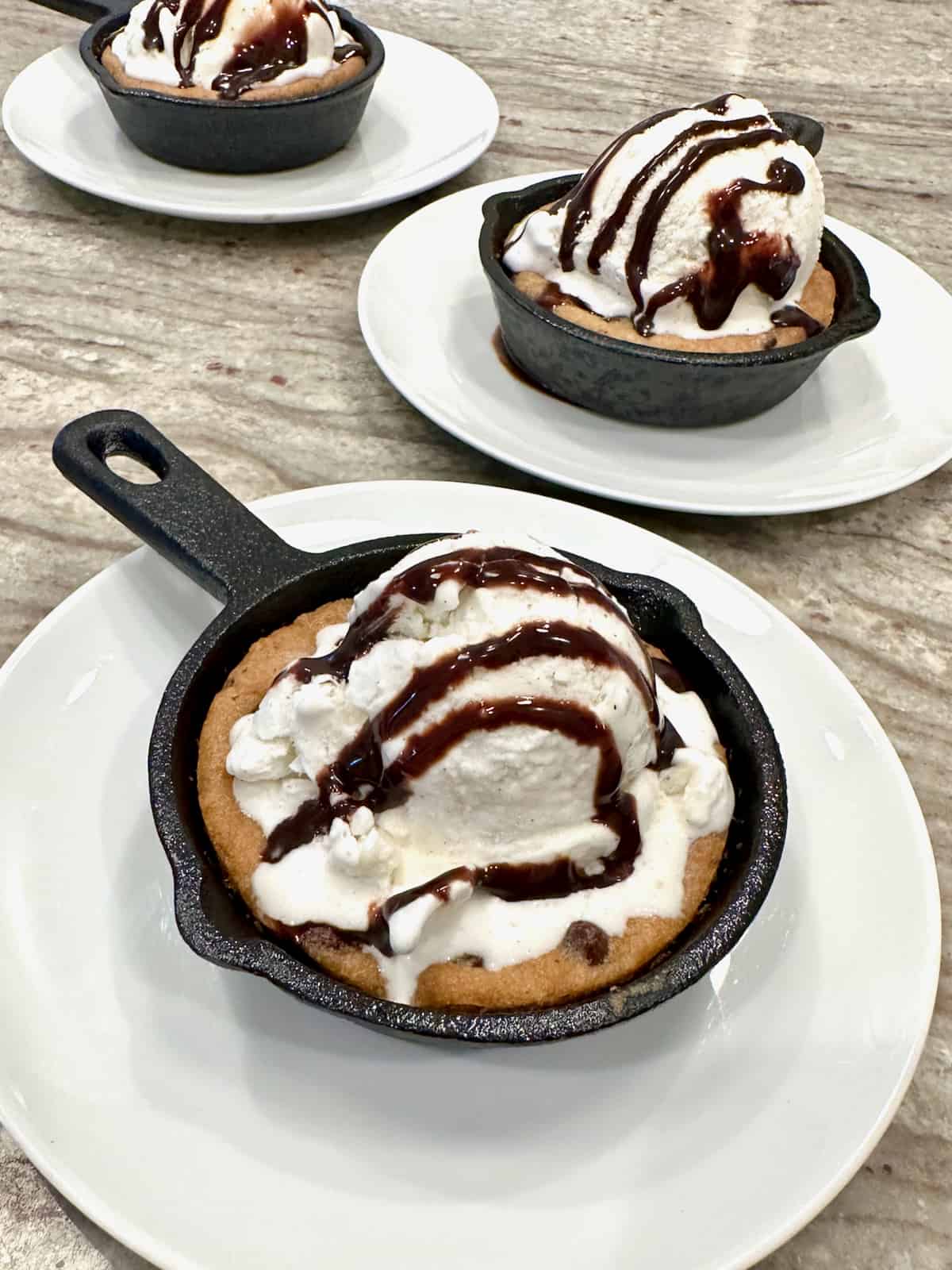 Chocolate chip cookies baked into three mini skillets and topped with ice cream and chocolate sauce.