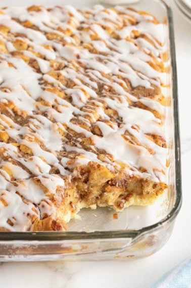 A 9x13 glass casserole dish with cinnamon roll breakfast casserole drizzled with icing.