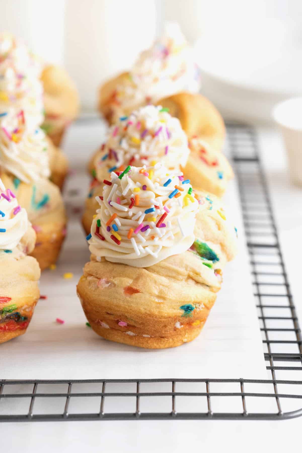 Six confetti cruffins on a wire cooling rack.