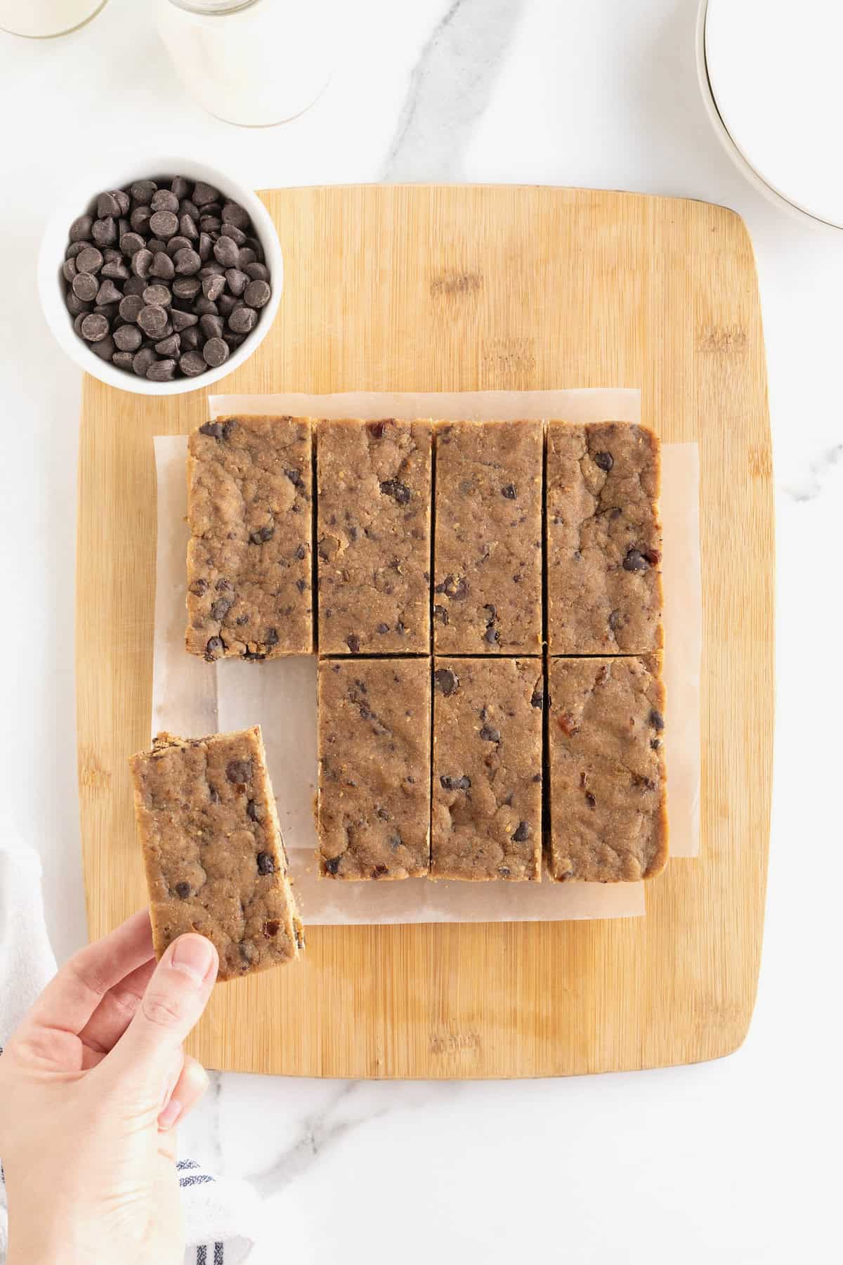 10 peanut butter chocolate chip breakfast bars on a parchment lined light wood cutting board.