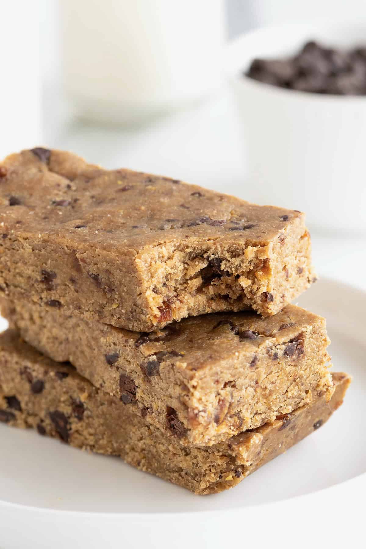 A stack of three peanut butter chocolate chip breakfast bars on a small white plate. The top bar has a bite out of it.