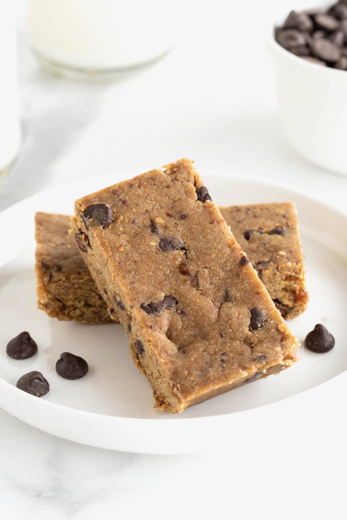 Two peanut butter chocolate chip breakfast bars on a small white plate. A few chocolate chips are scattered on the plate.
