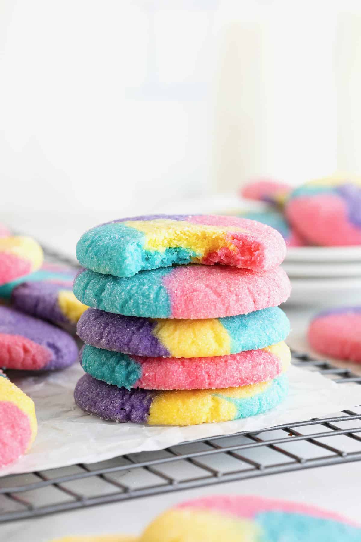 A stack of five multi-color cookies. The top cookie has a bite out of it.