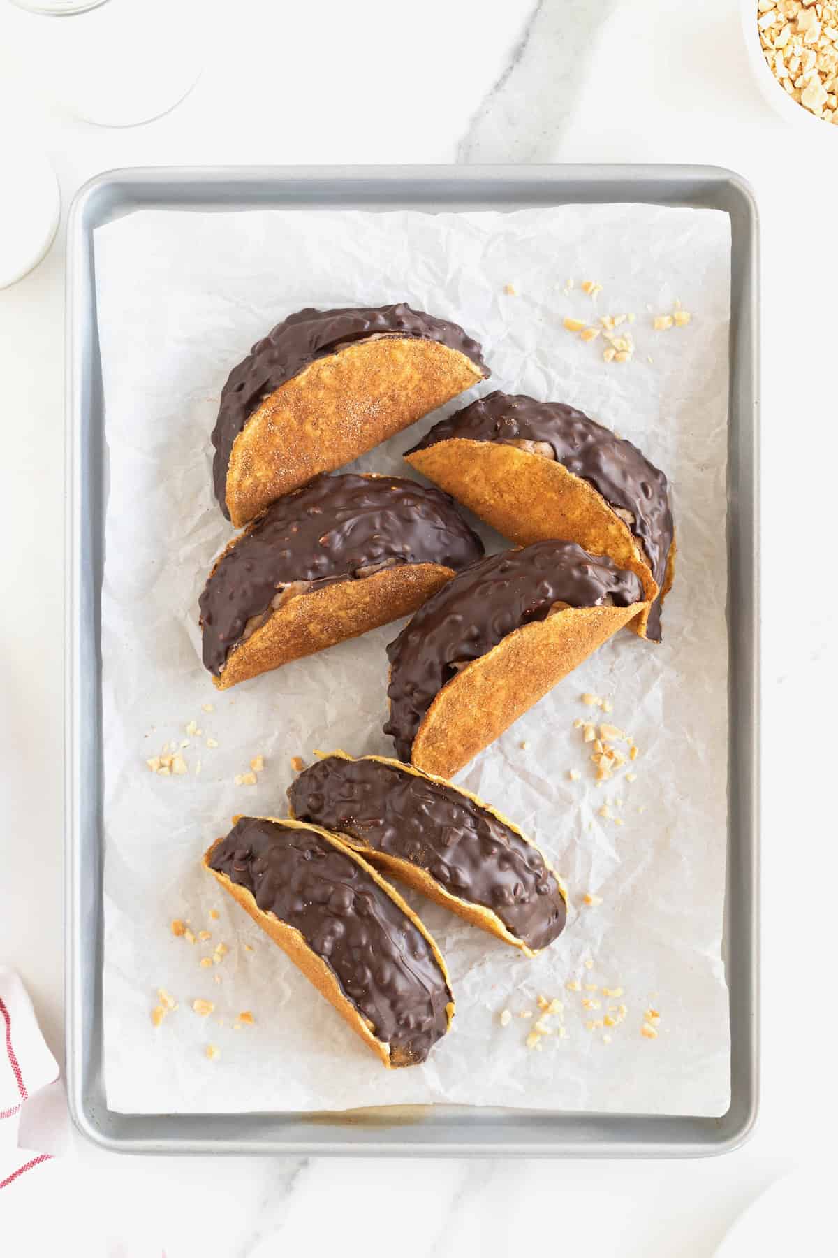 Six choco tacos on a parchment lined aluminum baking sheet.