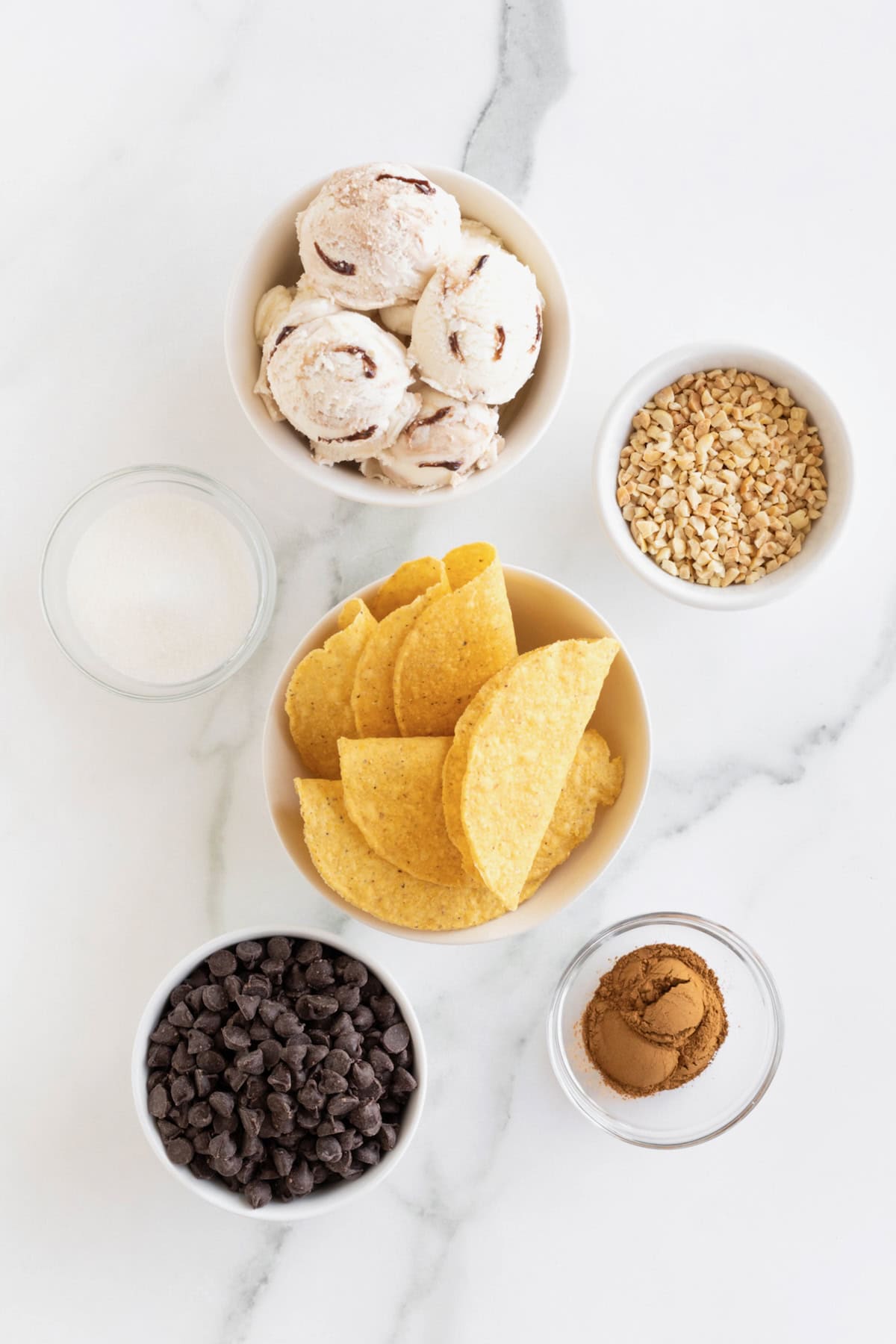 Ingredients to make chaco tacos in small glass dishes on a white marble counter.