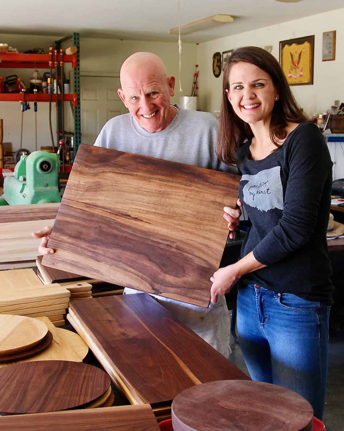 Maegan Brown and her father pose with a wood board in his shop.