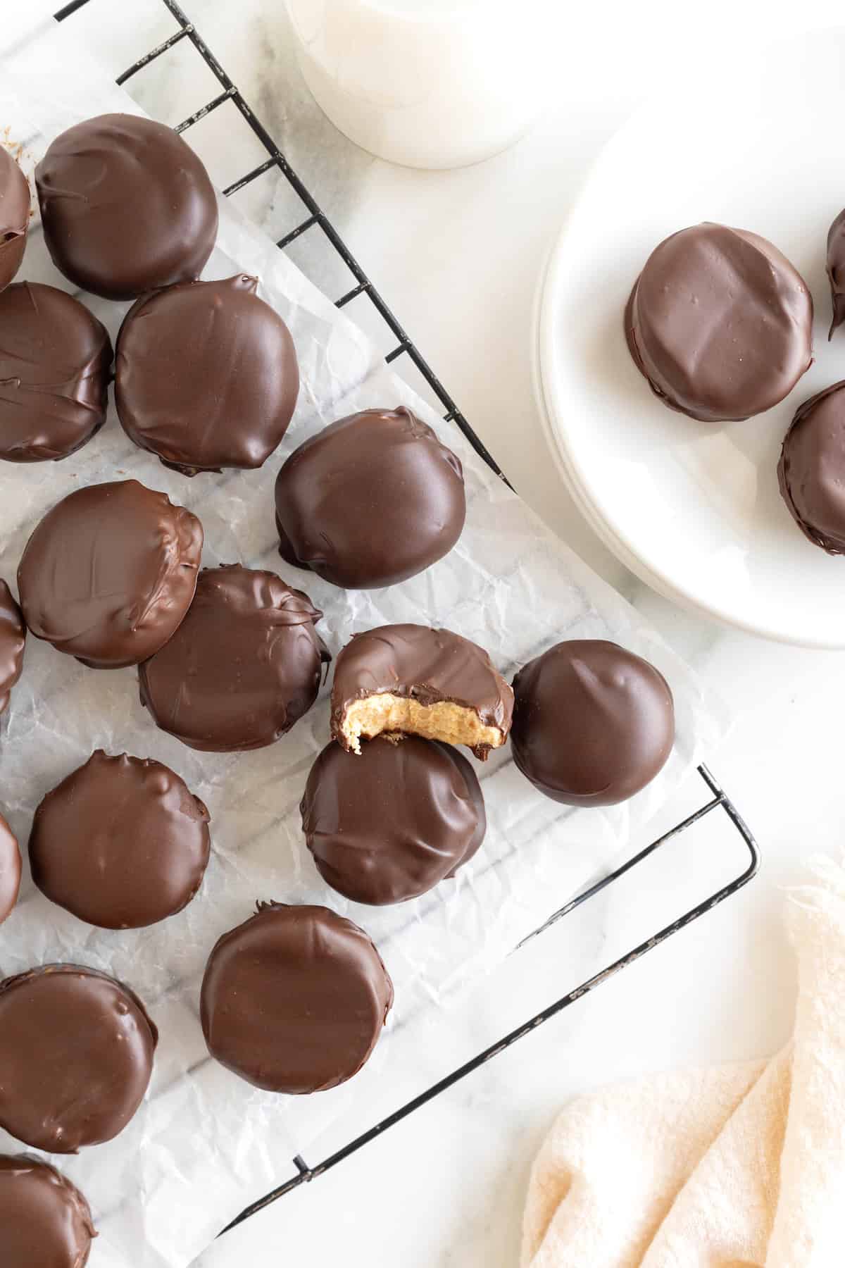 Homemade peanut butter cups piled on a parchment lined metal cooling rack.