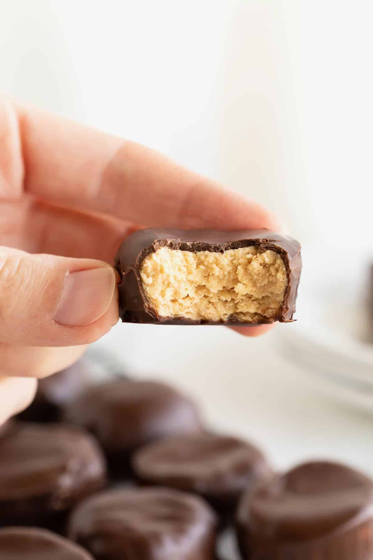 A hand holding a homemade peanut butter cup between thumb and forefinger.