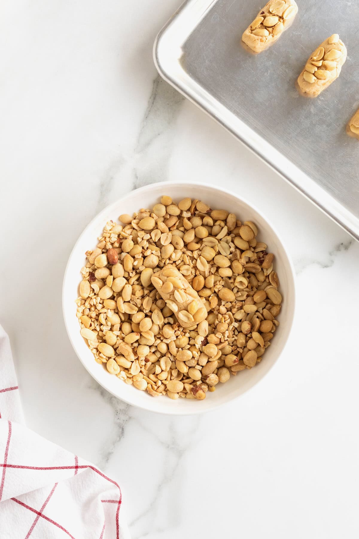 Payday candy bar bite dipped in peanuts in a small white bowl.