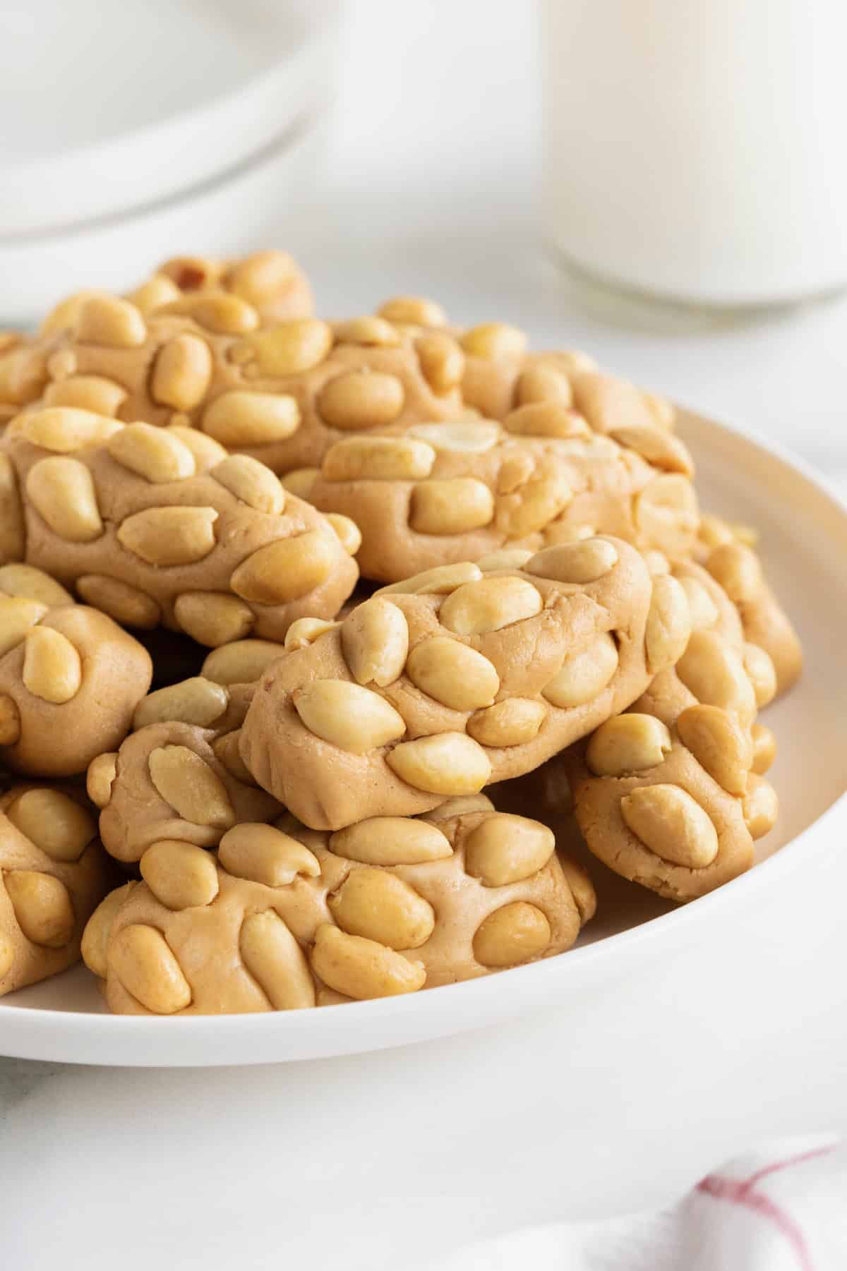 A large white plate of payday candy bar bites on a white counter.