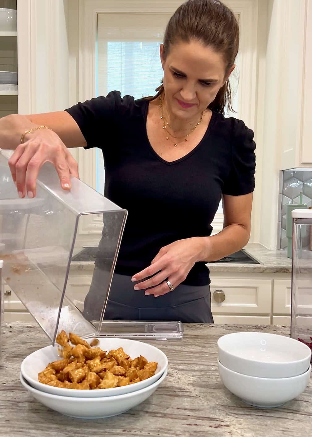 Maegan Brown duping cereal from a clear canister into a large bowl