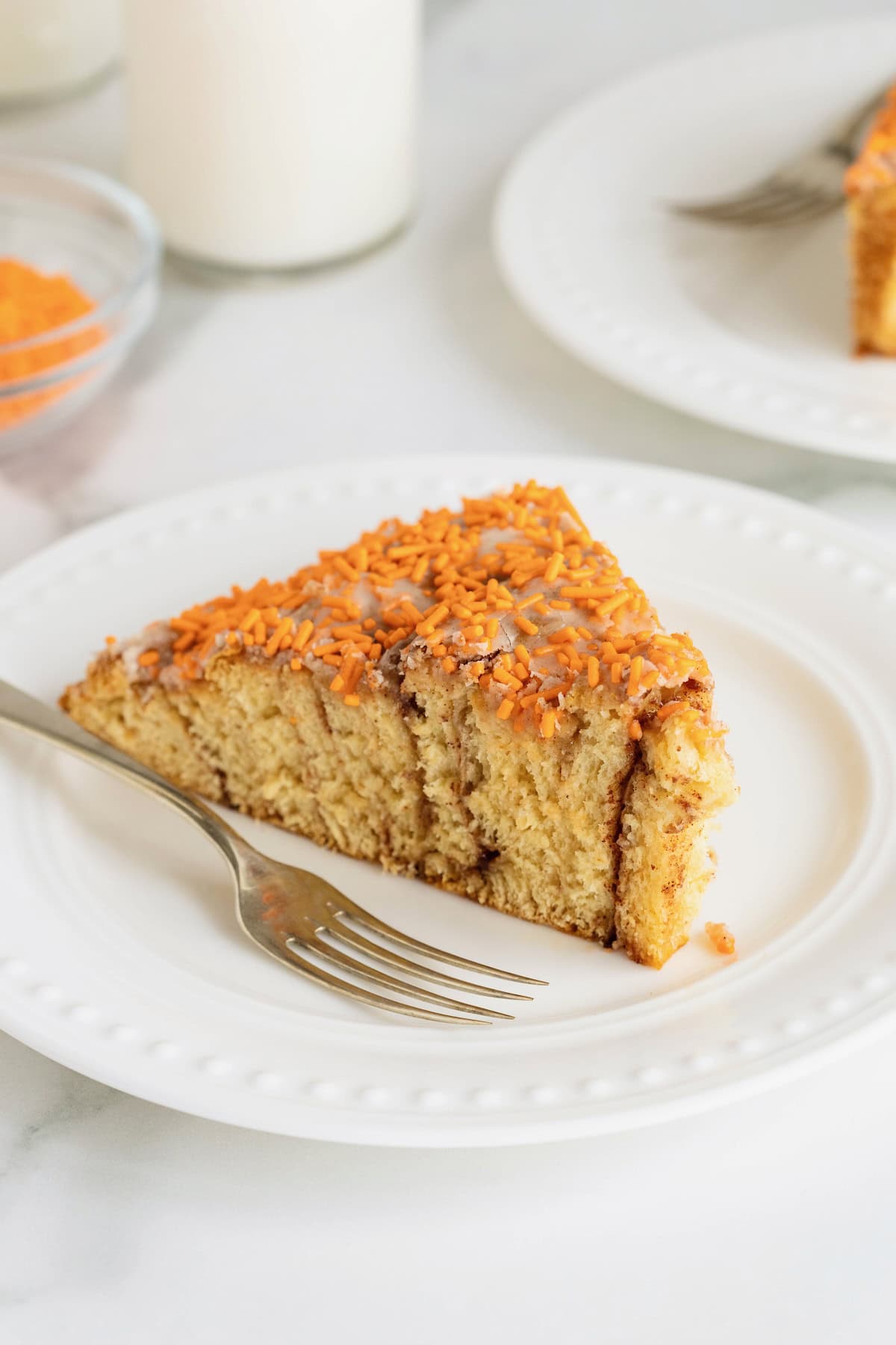 A slice of giant cinnamon roll pumpkin on a white plate with a fork. 