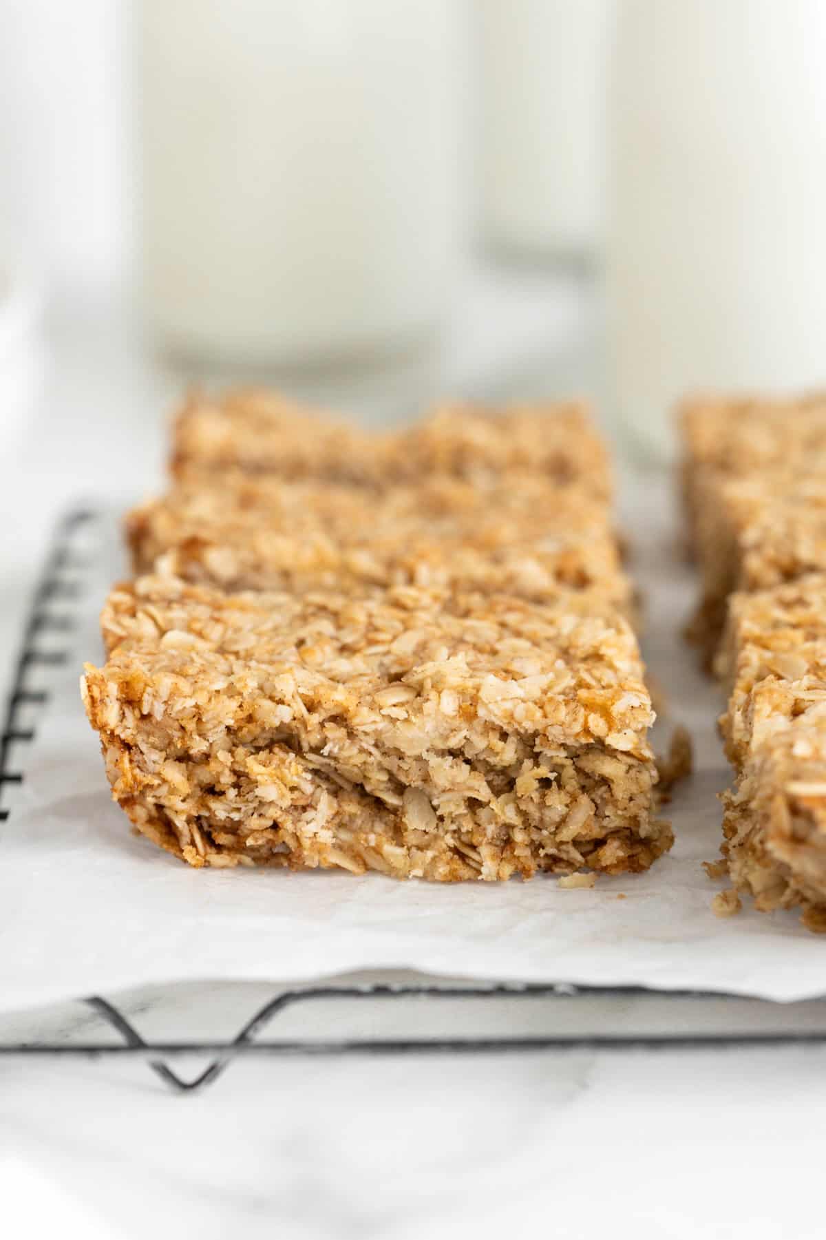 Eight oatmeal crunchies bars on a parchment lined cooling rack.