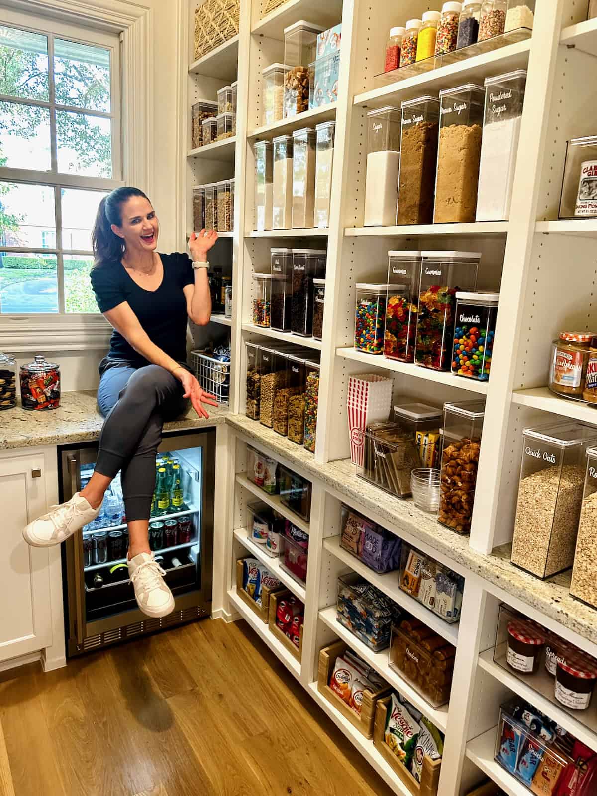 Maegan Brown sitting on the counter above her drinks fridge in her pantry.