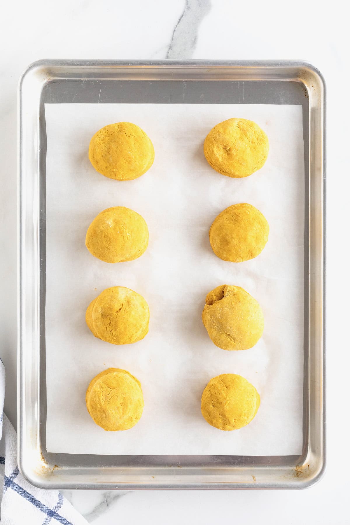 Eight pumpkin muffins on an aluminum baking tray lined with parchment.