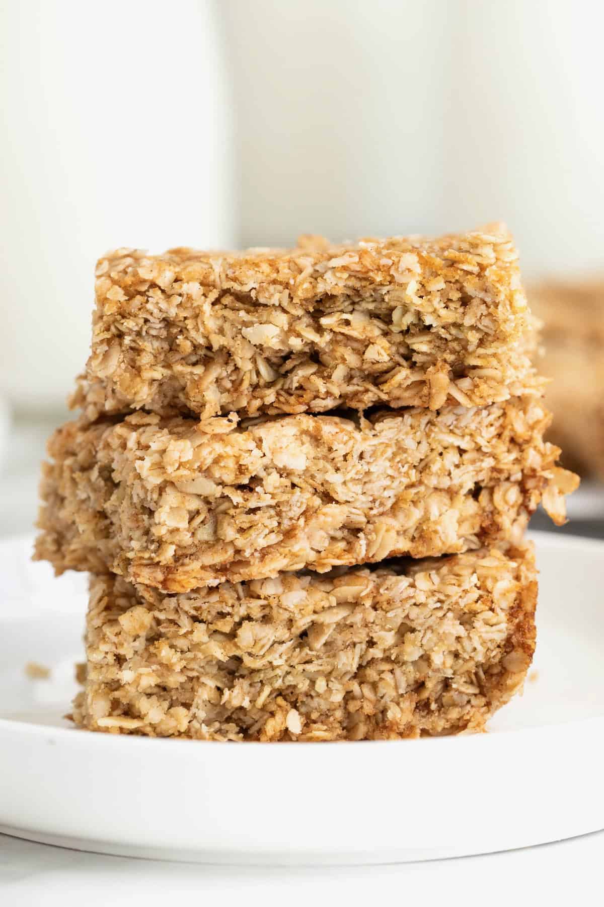 Three crunch oatmeal bars stacked on a small white plate.