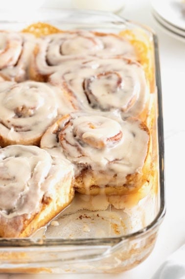 Store bought cinnamon rolls in a glass baking dish topped with icing.