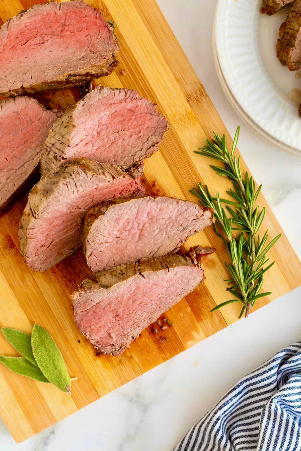 Sliced beef tenderloin on a wood cutting board.