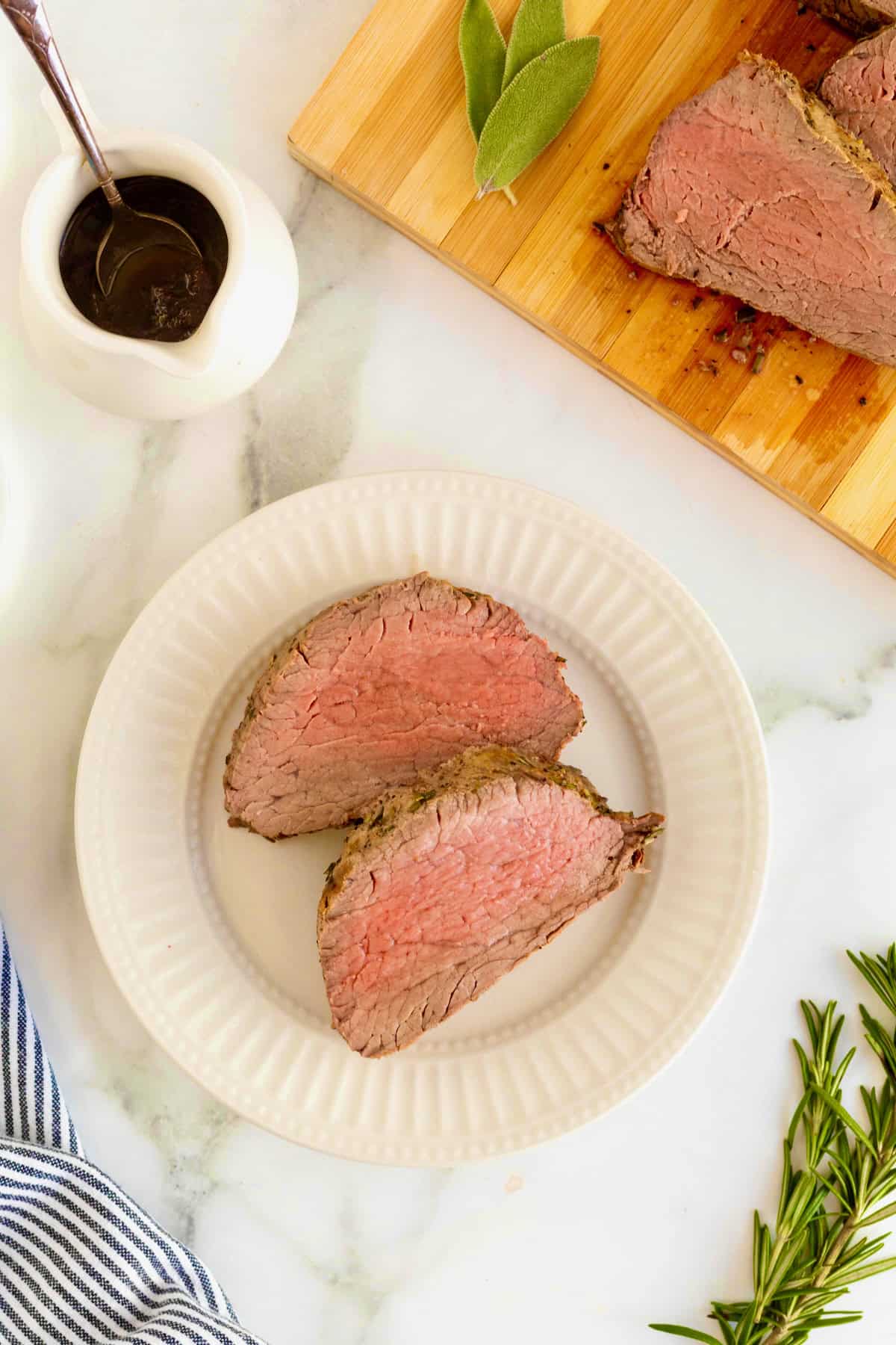 Two slices of beef tenderloin on a small white fluted plate.