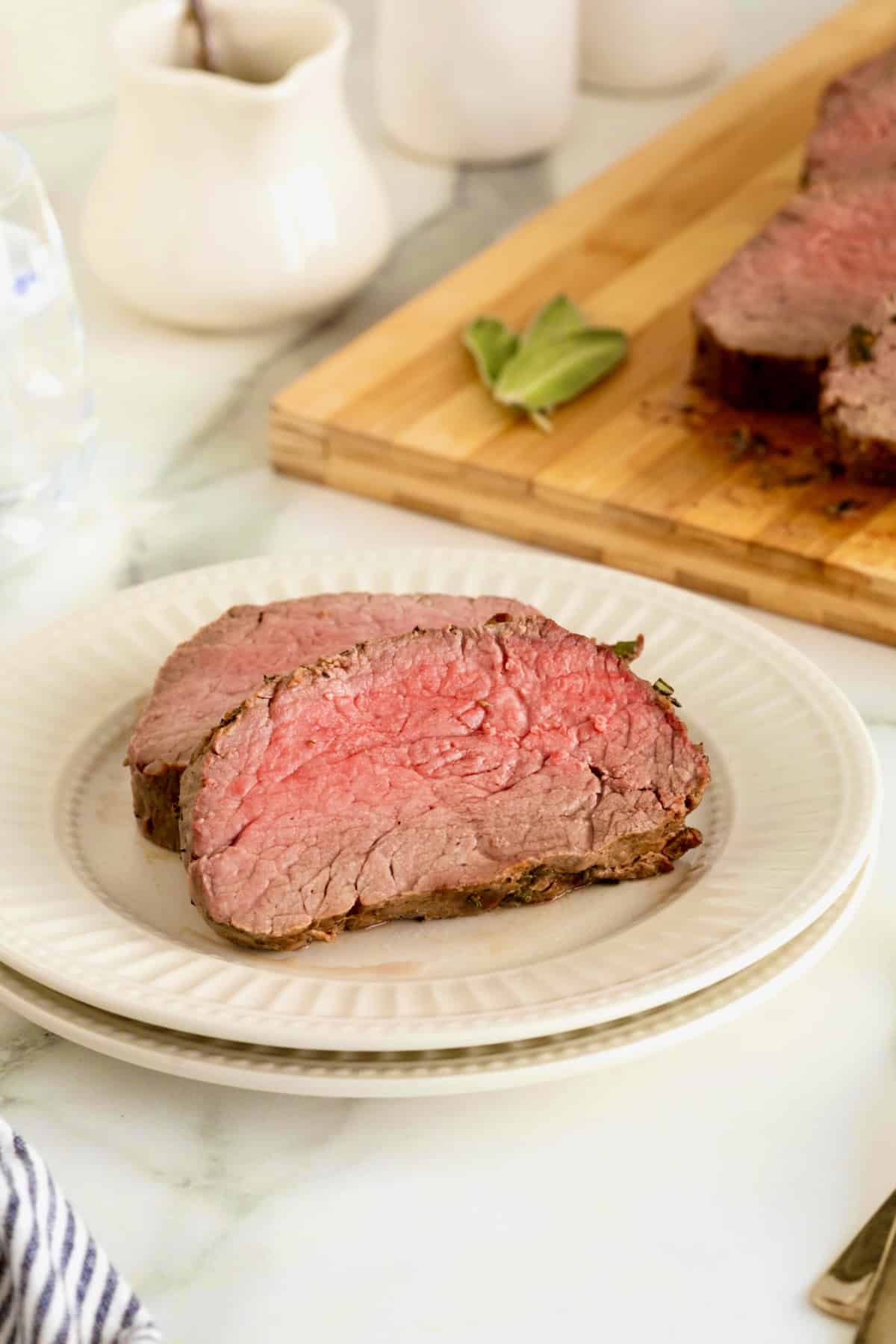 Two slices of beef tenderloin on a small white fluted plate.