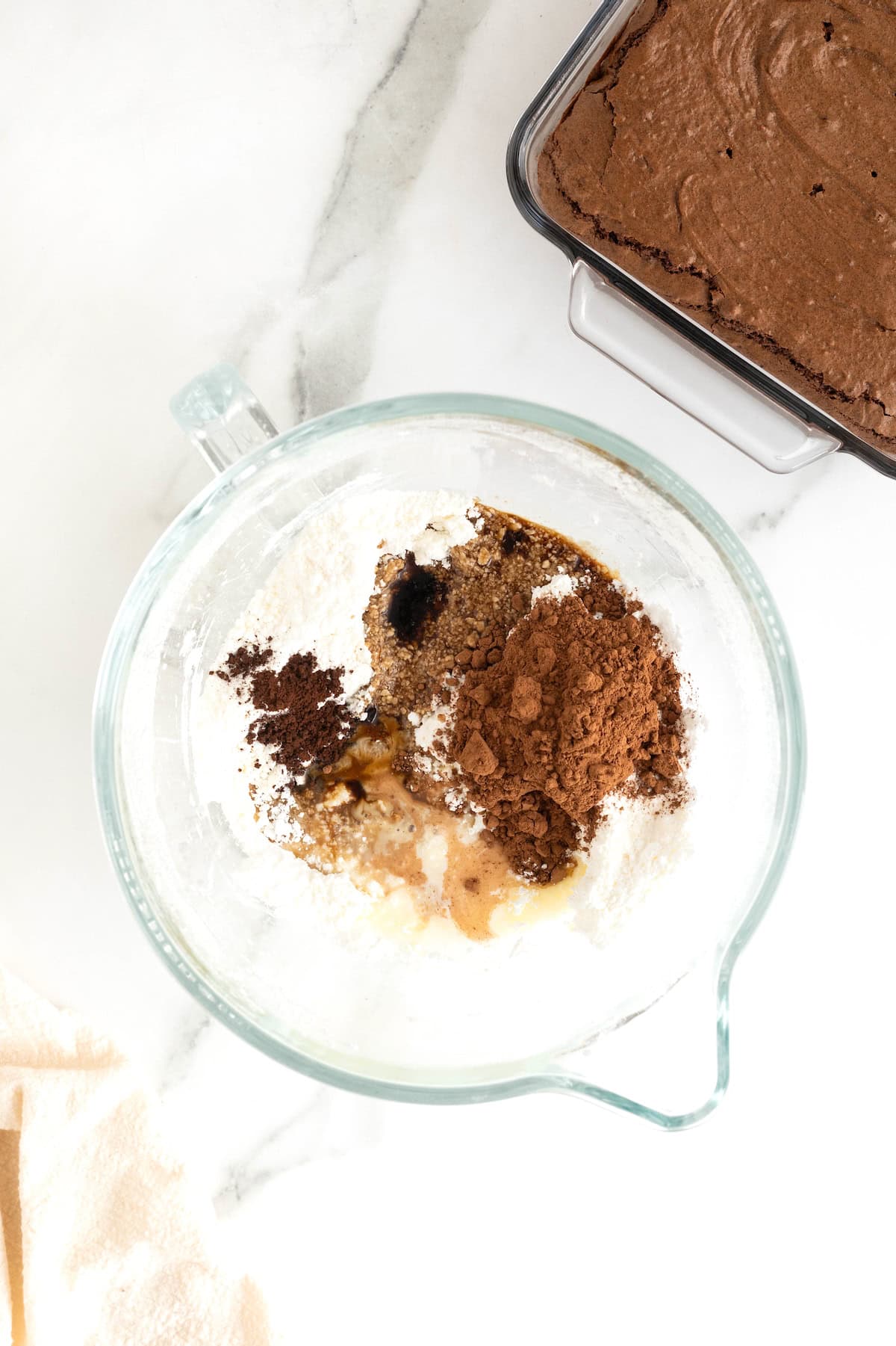 A glass mixing bowl with ingredients to make espresso buttercream frosting.