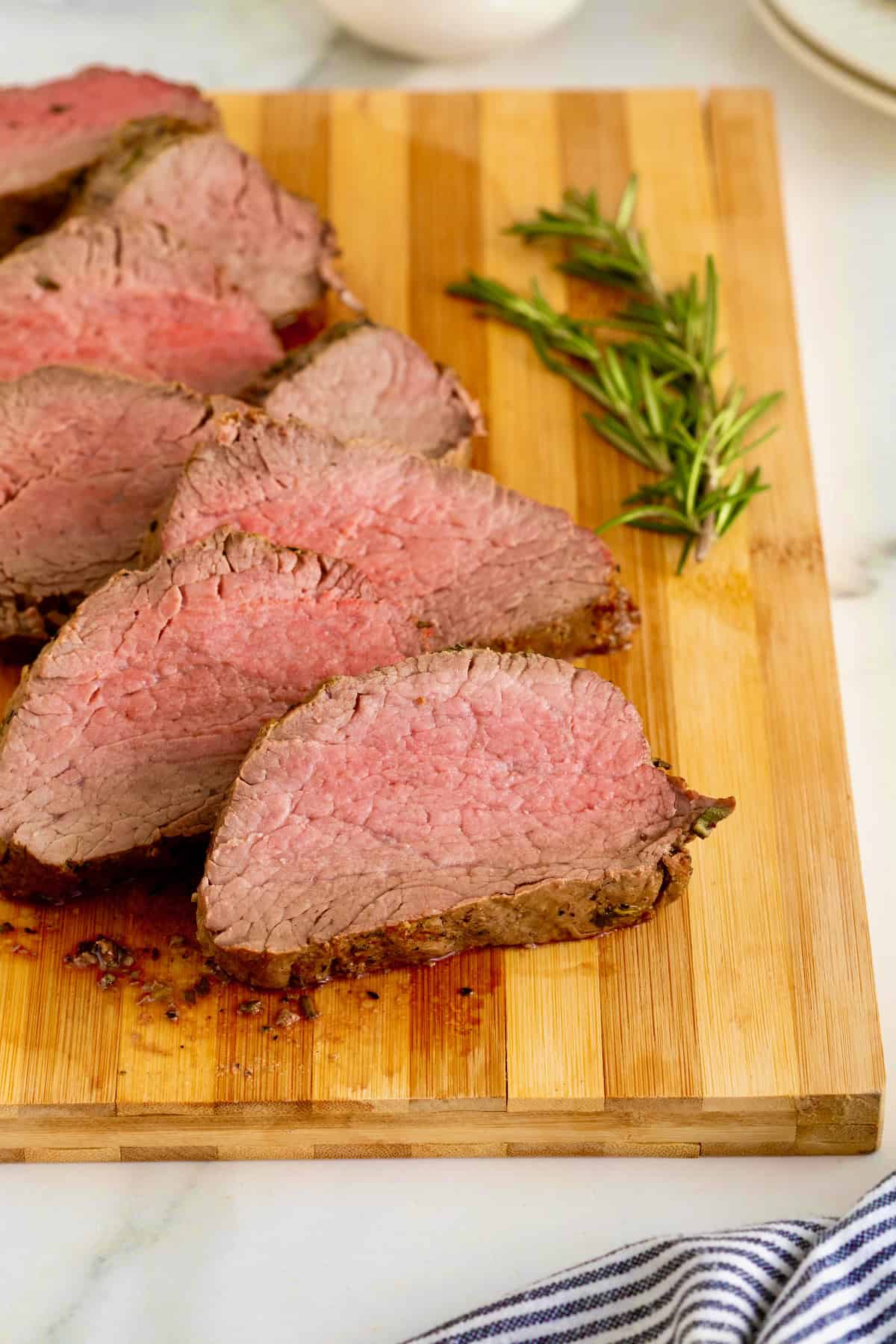 Sliced beef tenderloin on a wood cutting board.