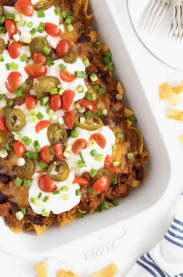 A white casserole dish of Frito Chili Pie casserole o a white marble counter.