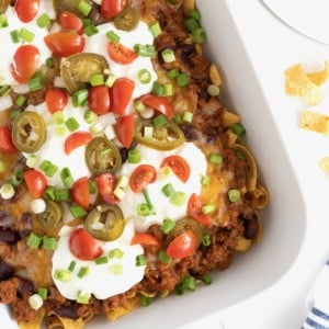 A white casserole dish of Frito Chili Pie casserole o a white marble counter.