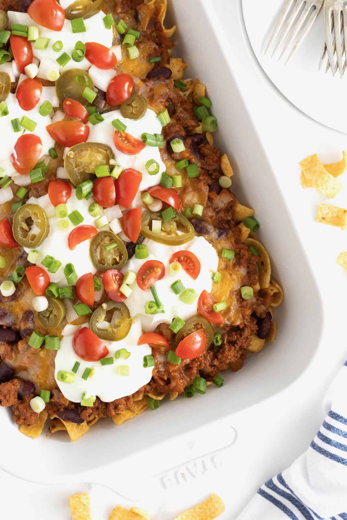 A white casserole dish of Frito Chili Pie casserole o a white marble counter.