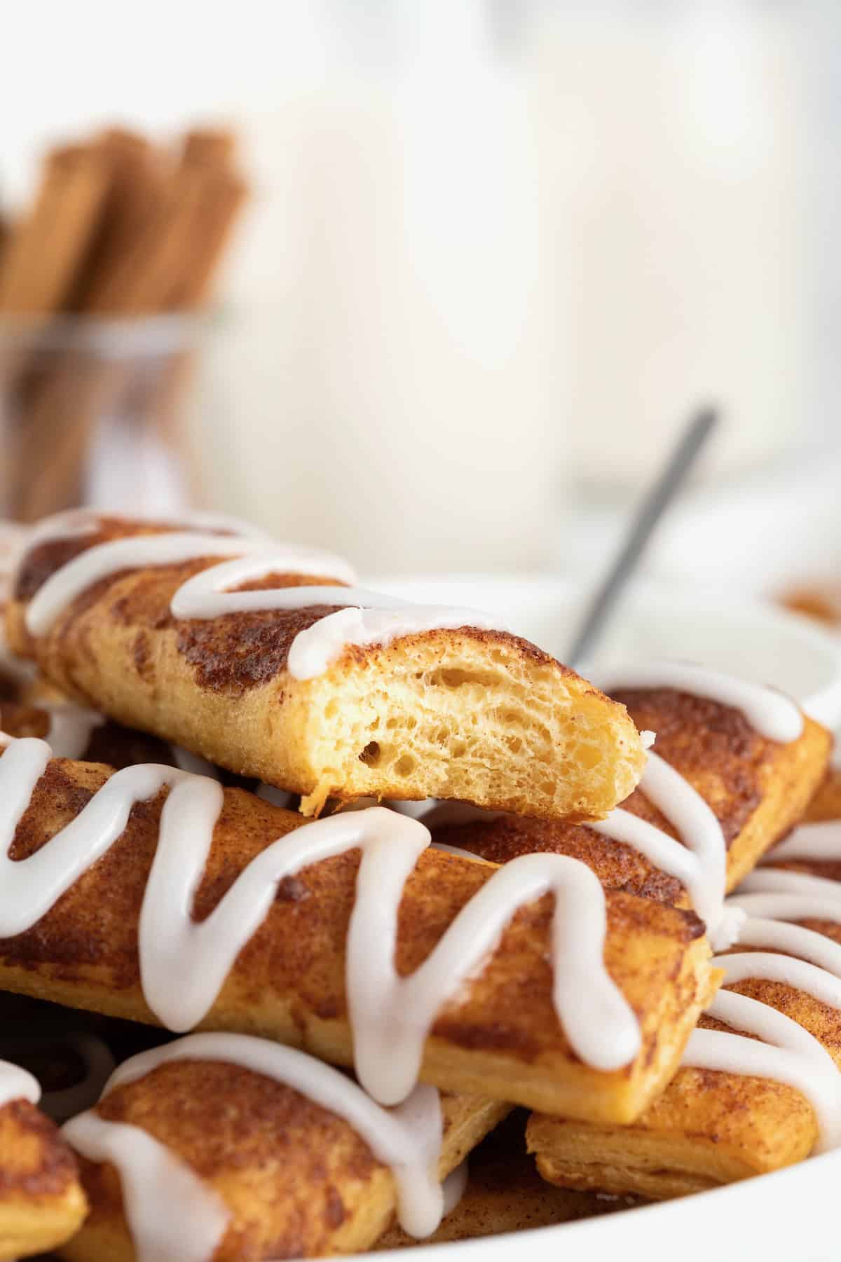 A cinnamon roll stick with a bite taken out of it.