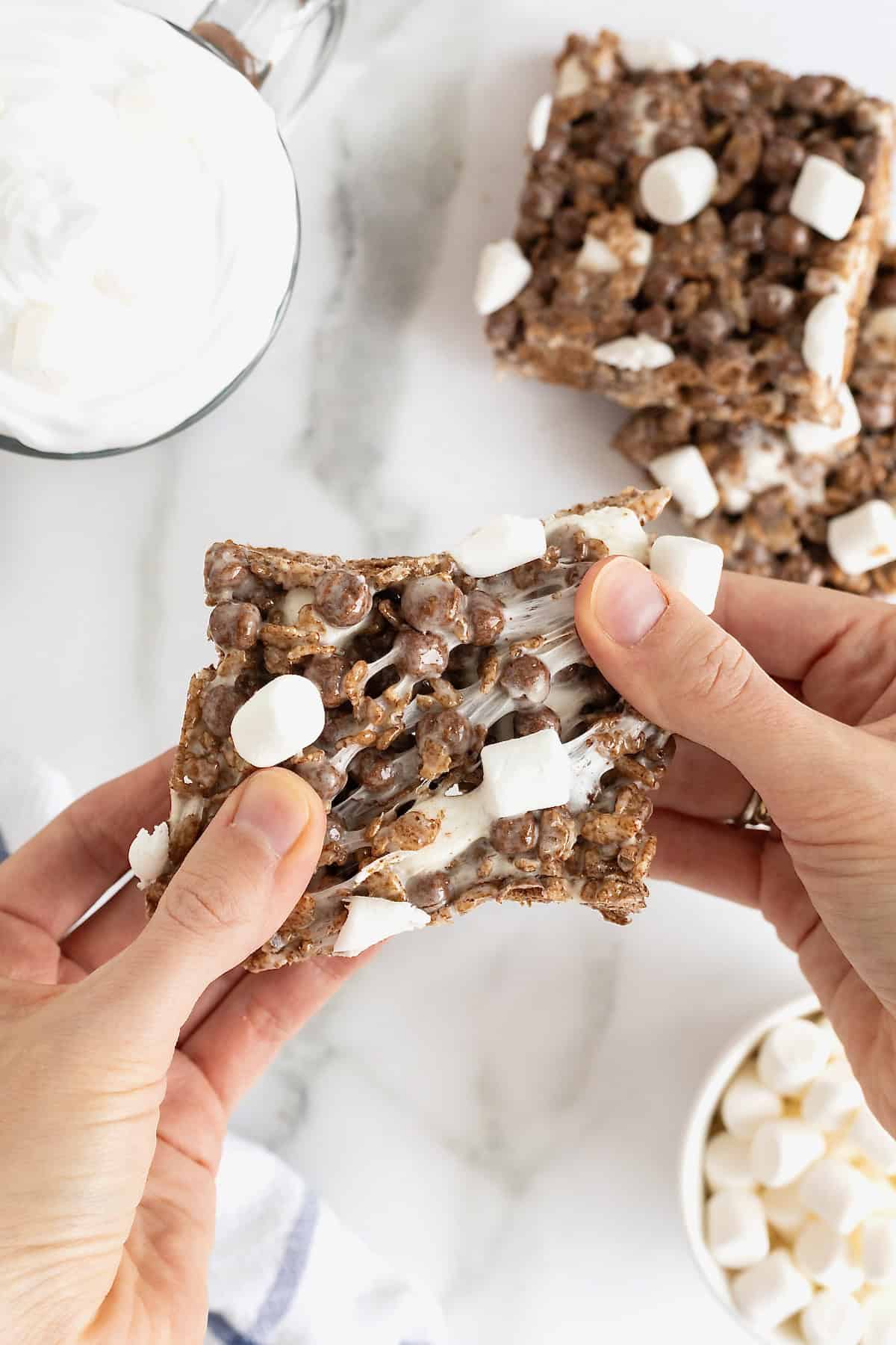 A pair of hands pulling apart a cocoa Krispie treat.